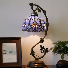 a lamp that is on top of a table next to a framed photo and potted plant