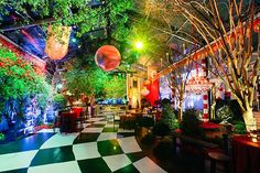 the interior of a restaurant at night with lights on trees and checkered flooring