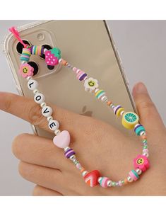 a person holding a cell phone with a beaded bracelet attached to it's wrist