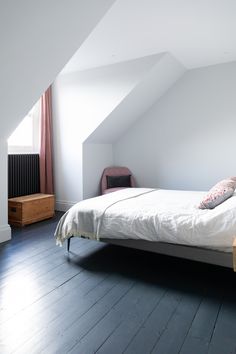 a white bed sitting in the middle of a bedroom next to a dresser and window