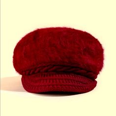 a red hat is sitting on a white surface and it's made out of wool