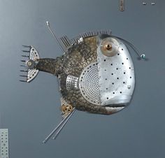 a metal fish sculpture sitting on top of a body of water next to other items