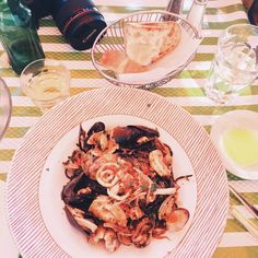 there is a plate of food on the table with wine and bread in the background