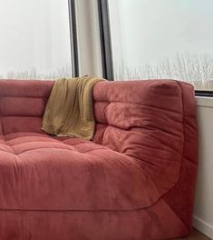 a red couch sitting in front of a window