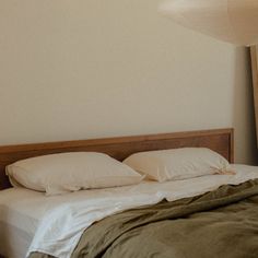 an unmade bed with white sheets and pillows