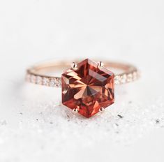 an orange diamond ring sitting on top of a white surface