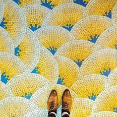 a person standing on top of a yellow and blue tile floor with their feet up