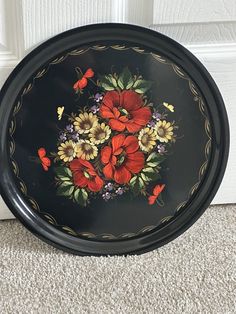 a black tray with red and yellow flowers painted on the side, sitting in front of a door