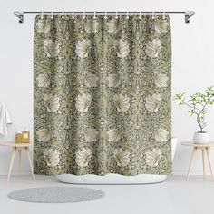 a green shower curtain with white flowers and leaves on it in front of a bathtub