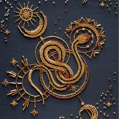 an intricately designed piece of art with gold and red beads on a black surface