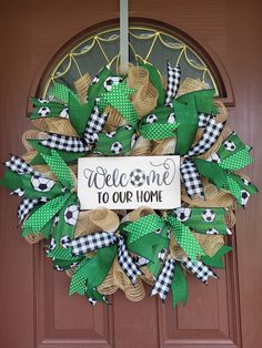 a welcome to our home wreath hanging on the front door with green and white decorations