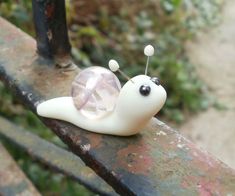 A small snail made with a clear white swirly marble for his shell, black seed beads for eyes, wire and clay antennae and body of white clay Snail Diy, Dark Marble, Clay Fairies, Clay Diy Projects, Clay Crafts Air Dry, Polymer Clay Diy