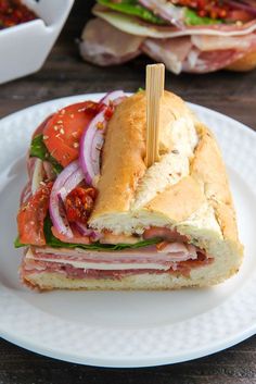 a sandwich with meat and vegetables on a white plate