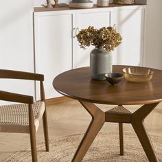 a wooden table with two chairs and a vase filled with flowers sitting on top of it