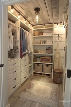 a walk in closet with lots of white drawers and baskets on the shelves next to it