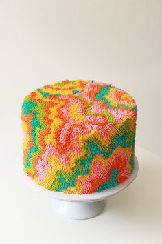 a multicolored cake sitting on top of a white table next to a wall