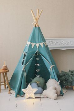 a teepee tent sitting on top of a white floor next to pillows and toys