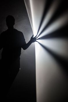 a man standing in front of a wall with a light shining through it