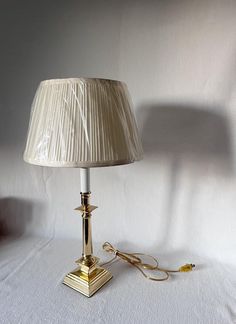 a lamp that is on top of a white sheeted surface with a cord attached to it