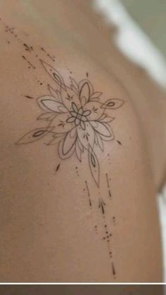 the back of a woman's shoulder with a flower tattoo on her left side