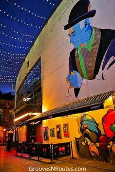 a large mural on the side of a building in front of a theater at night