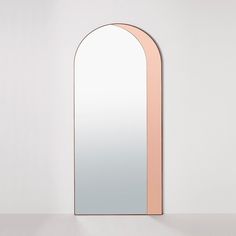 an arch shaped mirror is shown against a white wall, with pink trim on the edges