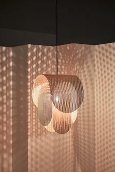 two lamps hanging from the ceiling in front of a curtained wall with shadows on it