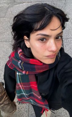 a woman with black hair wearing a plaid scarf