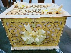 a decorative box sitting on top of a table with flowers in the front and sides