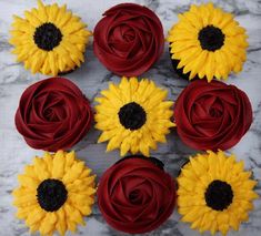 red and yellow cupcakes with sunflowers in the middle on a marble table