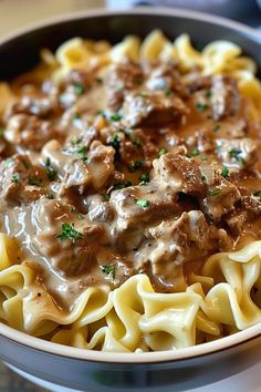 a bowl filled with pasta covered in meat and gravy on top of a table