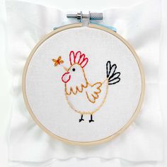 a white pillow with an embroidered chicken on it