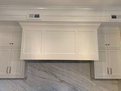 a kitchen with white cabinets and marble counter tops on the wall above it is an oven hood