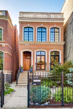 an old brick house with many windows and wrought iron fenced in walkway leading up to the front door