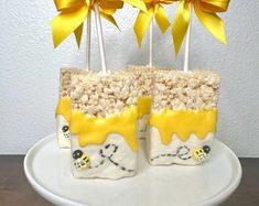 two cake pops decorated with yellow and white frosting, topped with marshmallows