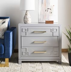 a grey chest of drawers with gold handles in a living room next to a blue couch