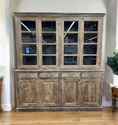 an old wooden cabinet with glass doors on the front and side, sitting in a living room