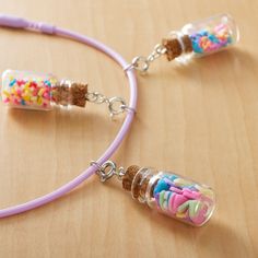 two necklaces with candy and sprinkles in them sitting on a table