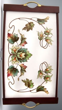 an artisticly designed tray with leaves and vines on it's sides, hanging from the wall