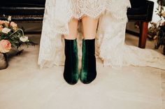 a bride's feet in green velvet boots and lace dress sitting on a bench