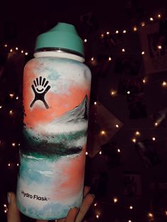 a hand holding up a water bottle with an image of a mountain and the words hydro flask on it