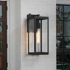 an outdoor wall light on the side of a white brick building with two lights attached to it