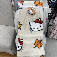 a hello kitty blanket is sitting on a chair in a store with other items nearby