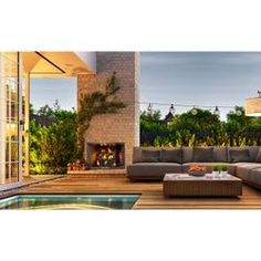 an outdoor living area with couches, tables and a fire place in the center