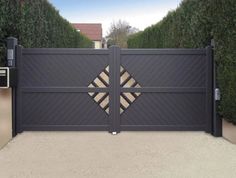 a modern gate with an intricate design on the top and bottom part, surrounded by hedges