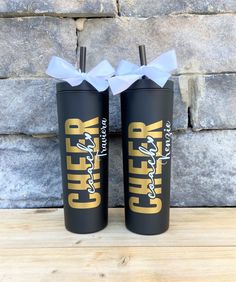 two black tumblers with white bows are sitting next to each other on a wooden table