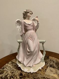 an angel figurine sitting on top of a table next to a white wall