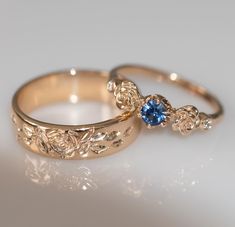 two gold wedding rings with blue stones on them