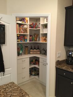 an open pantry in the corner of a kitchen with granite counter tops and white cabinets