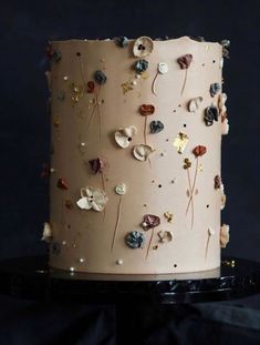 a close up of a cake on a black surface with flowers and leaves all over it